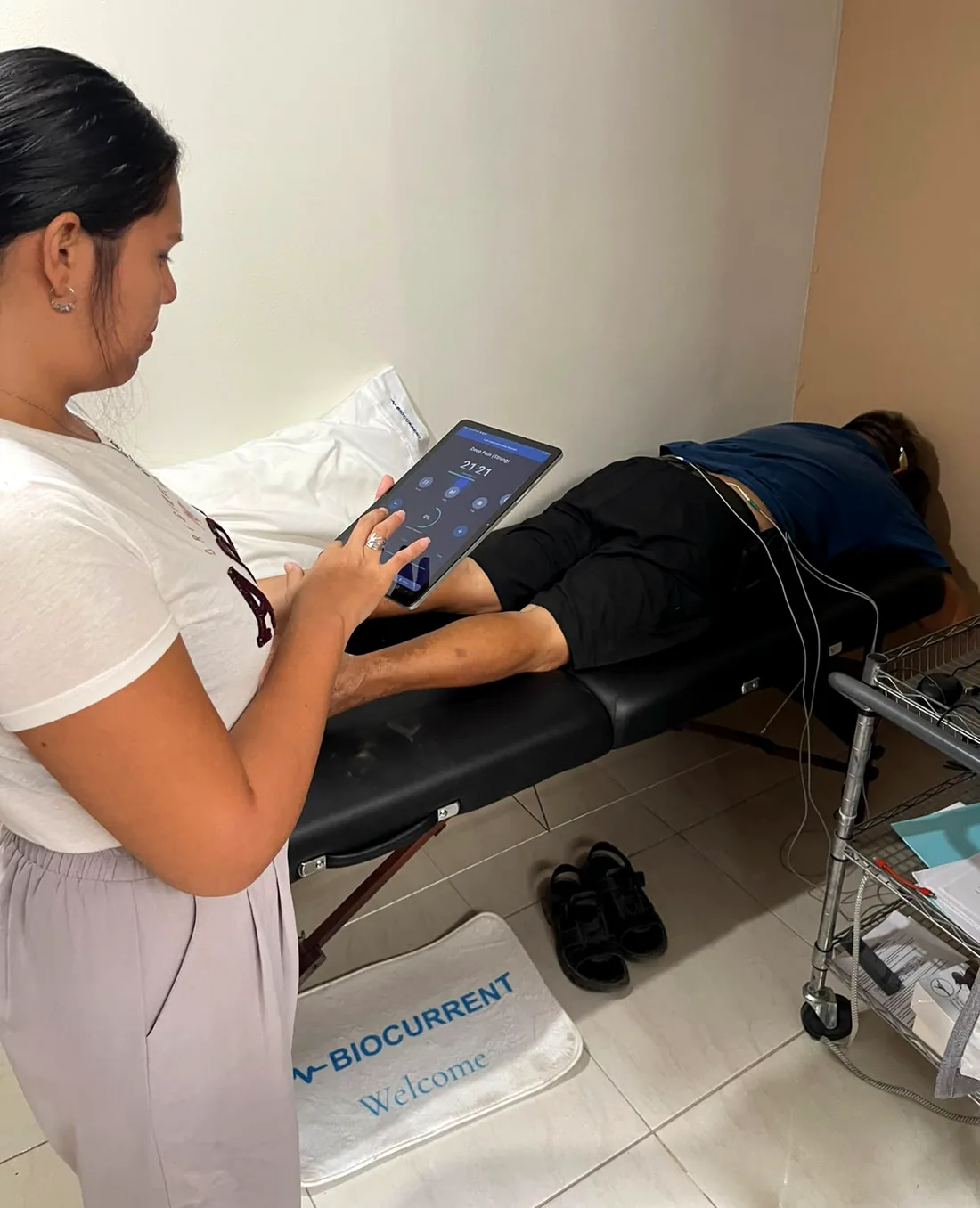 A clinician operates a tablet beside a participant during a Biocurrent research session in Puerto Vallarta, Mexico.